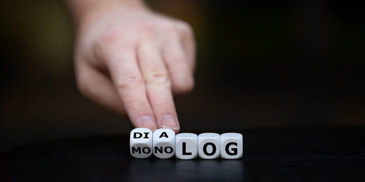 Hand dreht W&uuml;rfel und &auml;ndert das Wort "Monolog" in "Dialog".	