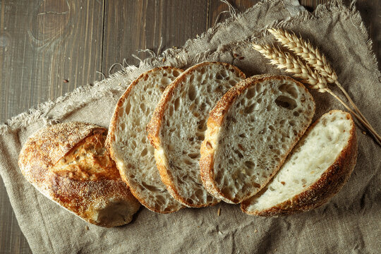 Bread, traditional sourdough bread cut into slices on a rustic wooden background. Concept of traditional leavened bread baking methods. Healthy food.