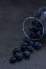Close up of blueberries falling out of a wine glass; dark  and moody