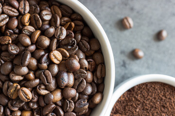 Close up of roasted coffee beans and ground coffee on grey backggound