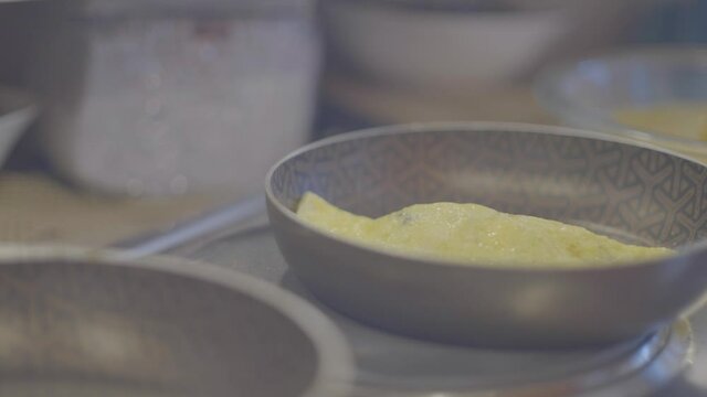 An omelet is being moved and prepared on a fancy pan in the kitchen.