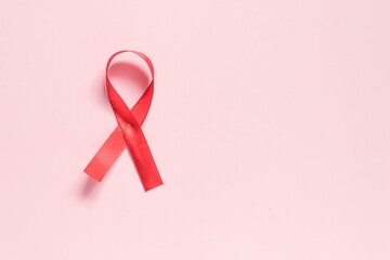 Red ribbon on a pink background. The concept of medicine and human health care. World breast cancer...