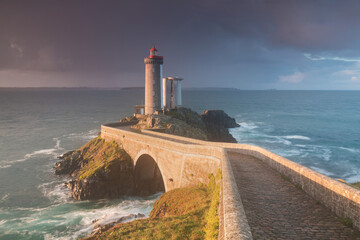 Most popular lighthouse in Europe during stormy weather. Petit Minou Lighthouse at sunset with red...