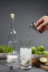 Mojito cocktail preparation. Man's hand pouring rum with a jigger into a glass