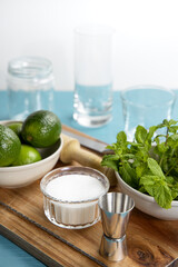 Mojito cocktail ingredients and tools on wooden cutting board
