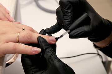 Fototapeta premium Close-up shot of nail polish by manicurist in black gloves