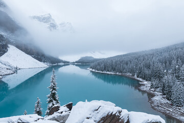 Fototapeta na wymiar First snow, Morning at Moraine Lake in Banff National Park Alberta Canada Snow-covered winter mountain lake in a winter atmosphere. Beautiful nature background photo. Landscape in the misty weather.
