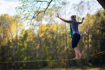 Woman balancing and jumping on slackline. Woman walking, jumping and balancing on rope in...