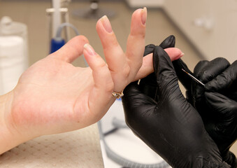 Close-up shot of nail polish by manicurist in black gloves