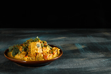Delicious indian food curry in brown dish on wooden table and dark background with copy space