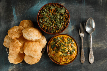 Delicious indian food curry in brown dish with bengali puff flatbread luchi and dal Indian food on wooden table top view