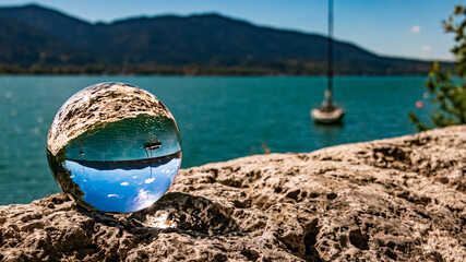 Crystal ball alpine landscape shot with a boat at the famous Tegernsee, Bavaria, Germany