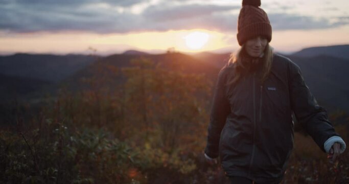 Cute smiling girl hiking over a mountain during the sunset over the Blue Ridges