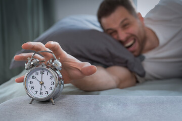 Angry Man Turning Off Alarm-Clock Waking Up Lying In Bed