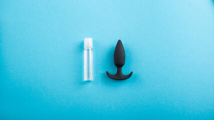 Top view of black anal plug and tube of lubricant on a blue background