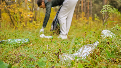 woman collects trash in a black bag in the woods close up.