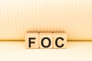Word FOC Abbreviation of Free of charge on wooden blocks on paper background top view