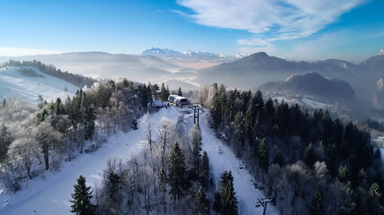 Winter in the white mountains and famous winter ski resort aerial view. Sunny winter day in alpine mountains. Winter holidays in Austria, Switzerland, Italy, Poland.