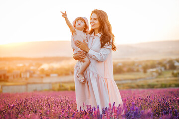 Happy family in a field at sunset. The kid smiles at his mother
