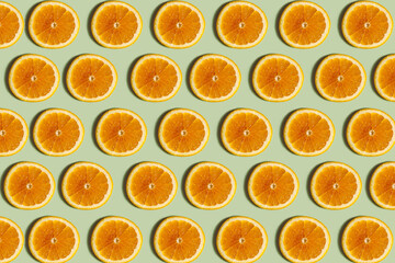 Orange pattern. Repetition of a round orange slice on a light green background. Top view of orange slices on a light surface. Horizontal. The concept of healthy food and vegetarianism.
