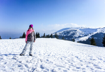Fototapeta na wymiar Smiling girl on the Kopaonik ski slope in ski clothes. Beautiful mountain view, winter landscape. Active lifestyle. Young woman