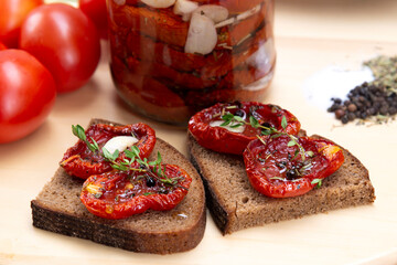 Homemade sun-dried tomatoes with olive oil in a glass jar. Sandwich with black bread and sun-dried tomatoes