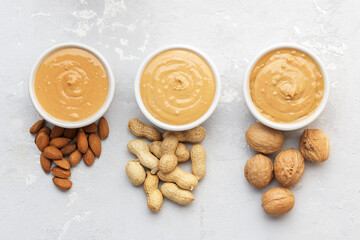 Walnut butter made of peanuts, almonds and walnut on a grey background.