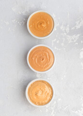 Walnut butter made of peanuts, almonds and walnut on a grey background.