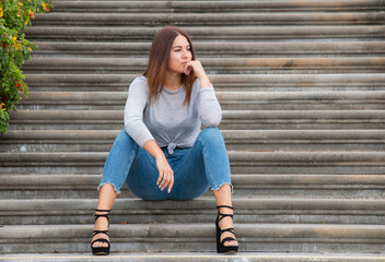 beautiful brunette girl outdoors sitting on concrete steps
