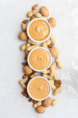 Walnut butter made of peanuts, almonds and walnut on a grey background.