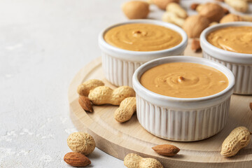 Walnut butter made of peanuts, almonds and walnut on a grey background.
