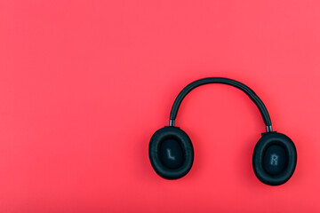 Wireless black headphones on a red background. View from above.