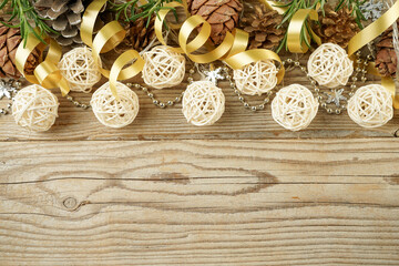 Christmas composition of garlands, pine cones and Golden ribbons with a copy space on a wooden background for a greeting card
