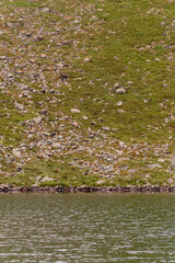 Beautiful and picturesque Carpathian lake Brebeneskul, a guy on the edge of the lake, the edge of the mighty mountains, a lake in the valley.
