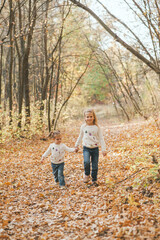 Fototapeta premium Two cheerful small sisters walking in the park in warm autumn day