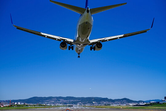 青空の広がる空港と着陸するジェット旅客機