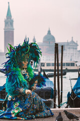 Famous carnival in Venice, Italy. Woman in blue mask feed pigeons.
