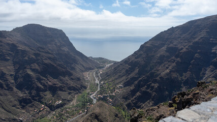 Paisaje de montañas con mar y nubes de fondo
