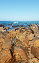 A lot of rocks and the sea in the background. The sky is blue.