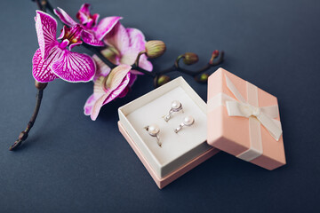 Set of jewellery. Silver ring and earrings with pearls in gift box with purple orchid. Fashionable accessories