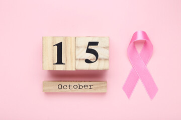 Cancer concept. Ribbon and wooden calendar on pink background