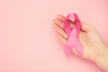 Breast cancer concept. Female hand holding pink ribbon