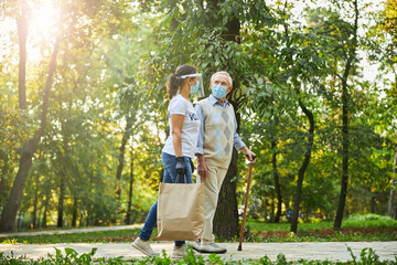 Fototapeta premium Happy person in casual clothes and protective medicine mask walking through the park