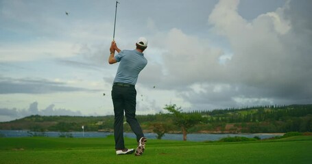 Playing golf on beautiful luxury resort golf course, man hitting golf ball in slow motion