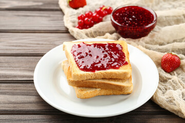 Toast with raspberry jam in plate on wooden table