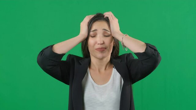 Horrible, stress, shock. Female portrait isolated at green screen background. Young emotional surprised woman clasping head in hands. Human emotions, facial expression concept. Choma key footage