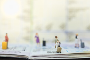 Fototapeta premium Travel Concept. Group of traveler miniature figure people with baggage on passport with immigration stamped and map as background.