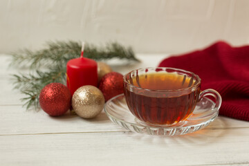 Obraz na płótnie Canvas Cup of tea with a candle and Christmas decorations, Christmas tree on a white wooden background.