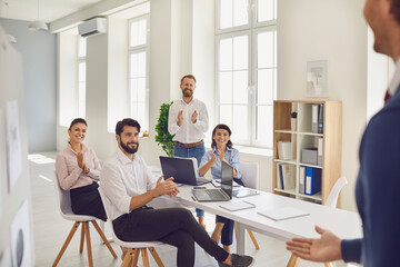 Group of thankful office workers applauding colleague for good presentation in a corporate meeting