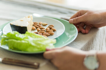 Plate with cheese, nuts and lettuce on the table, healthy food concept.